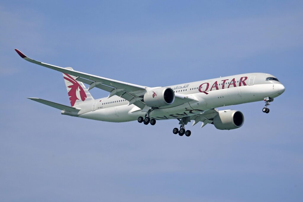A Qatar Airways Airbus A350 soaring through a clear blue sky, showcasing its modern design.