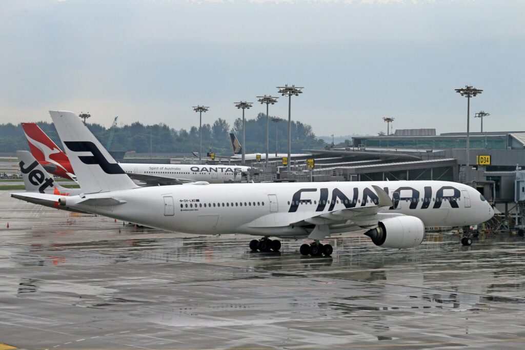 A Finnair airplane parked at a wet airport terminal with other aircraft nearby.