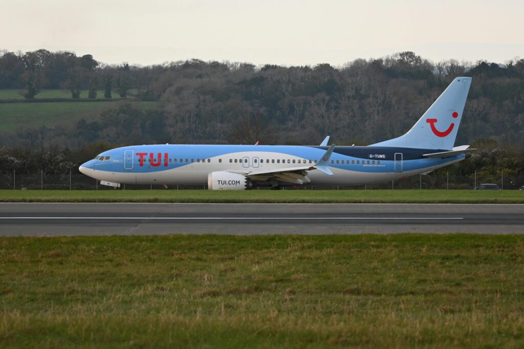 TUI airplane taxiing on the runway at a scenic airport.