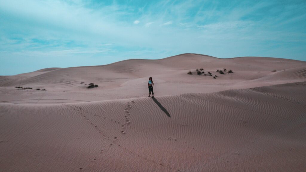 Explore the vast sand dunes of Dubai with footprints leading to adventure.
